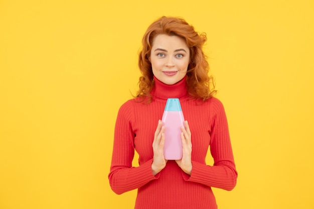 Vrouw met shampoo en conditioner roodharig krullend haar vrouw met biologische shampoofles mooi roodharig meisje met een fles shampoo meisje met glanzend krullend lang haar vrouw lang haar