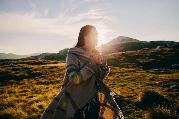 Vrouw met sjaal die op de berg tegen de lucht staat