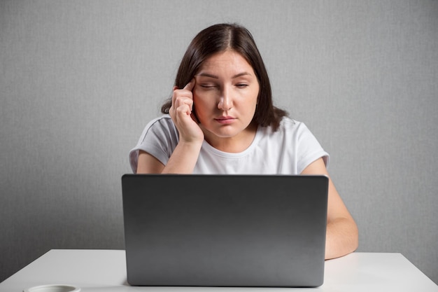 Vrouw met slecht gezichtsvermogen kijkt naar laptopscherm loensend