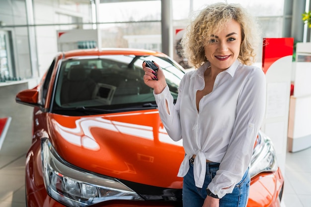 Vrouw met sleutel in handen in de buurt van nieuwe auto