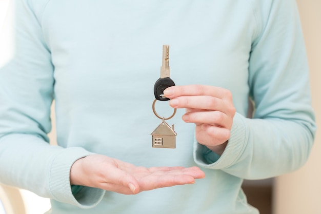 Vrouw met sleutel met sleutelhanger in de vorm van het huis