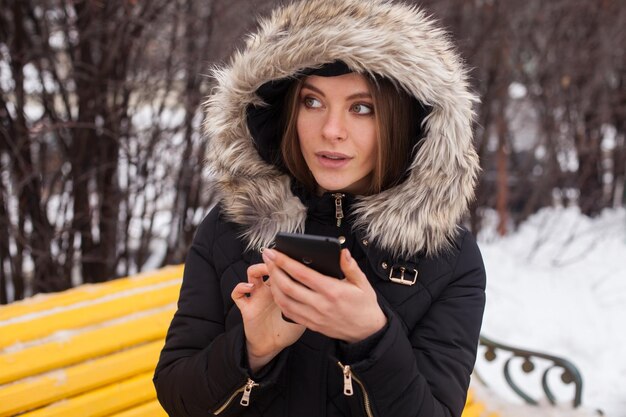 Vrouw met smartphone, bellen. Winter seizoen.