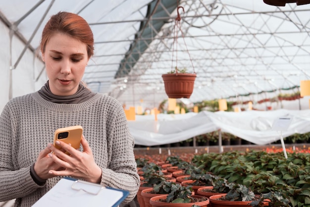 Vrouw met smartphone in professionele kas