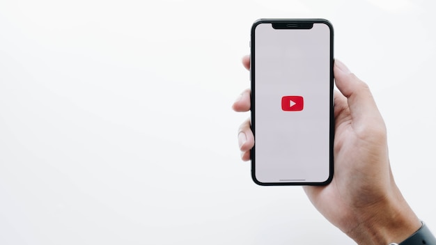 Vrouw met smartphone met Youtube app op het scherm