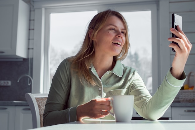 vrouw met smartphone videochatten of thuis lezen