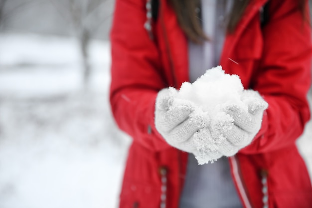 Vrouw met sneeuw in handen op winterdag, close-up