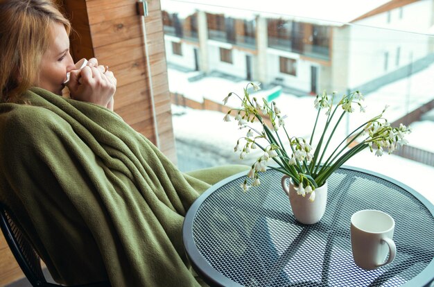 Vrouw met sneeuwklokjes en drinkbekers op het balkon wintertijd