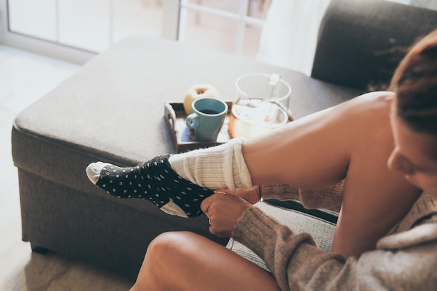 Vrouw met sokken op terwijl ze thuis op de bank zit
