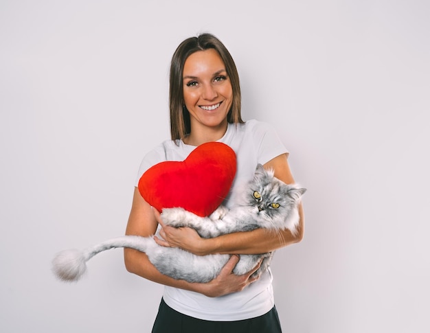 Foto vrouw met speelgoed met rood hart die haar lieve kat in haar armen houdt liefde voor huisdieren