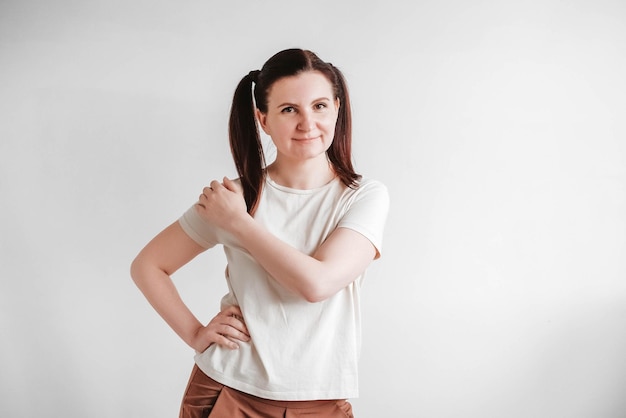 Vrouw met staartjes en een grappig gezicht, gekleed in een T-shirt op een witte achtergrond. Kopiëren, lege ruimte