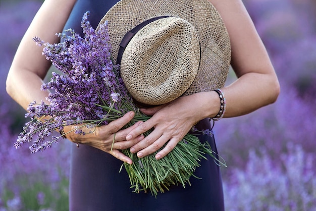 vrouw met strohoed en lavendelboeket in haar handen in lavendelveld in de zomer.