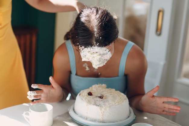 Foto vrouw met taart op haar gezicht thuis.