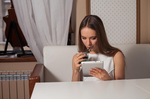 Vrouw met tablet en drank in café