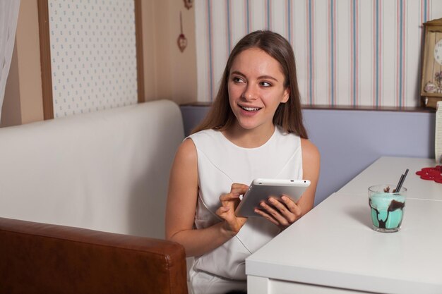 Vrouw met tablet en drank in café