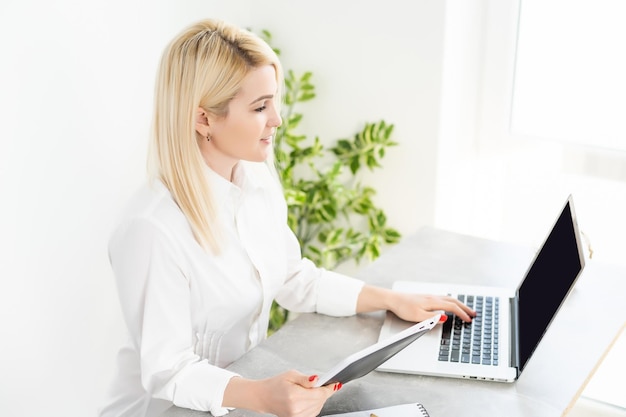 Vrouw met tablet. mooie jonge vrouw die op haar laptop in haar kantoor werkt.