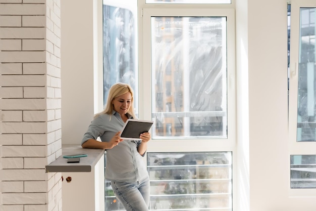 vrouw met tablet op zoek naar schoonmaak om vuile ramen te wassen