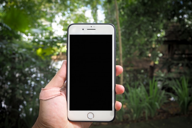 Foto vrouw met telefoon in de tuin.