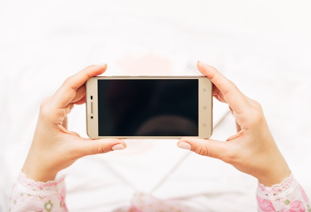 Vrouw met telefoon in haar handen. bespotten met zwarte screen.focus op phone.top view