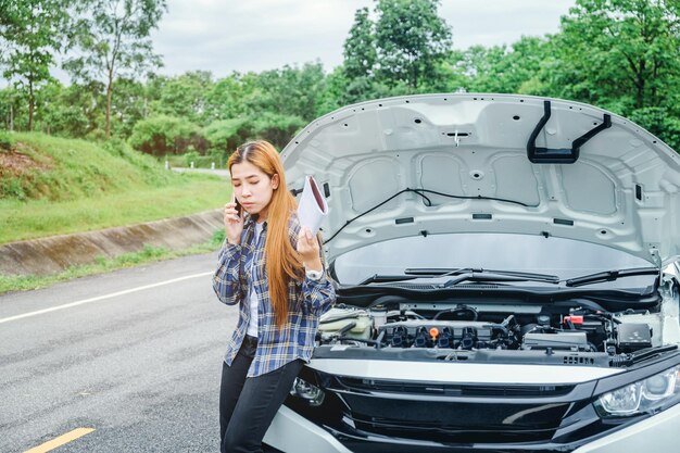 Vrouw met telefoon terwijl ze bij de auto staat op de weg