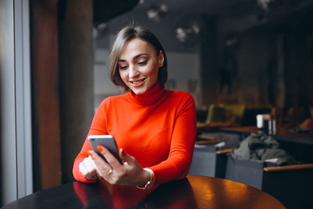 Vrouw met telefoon zit in een café