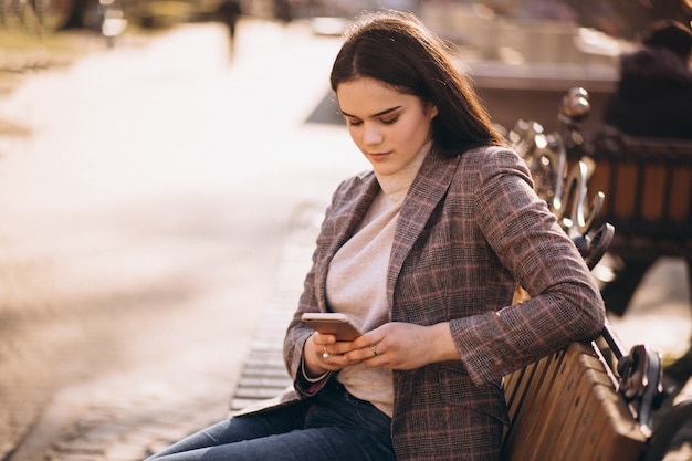 Vrouw met telefoon zittend op een bankje