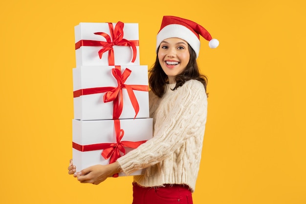 Vrouw met toren van kerstcadeau dozen op gele achtergrond