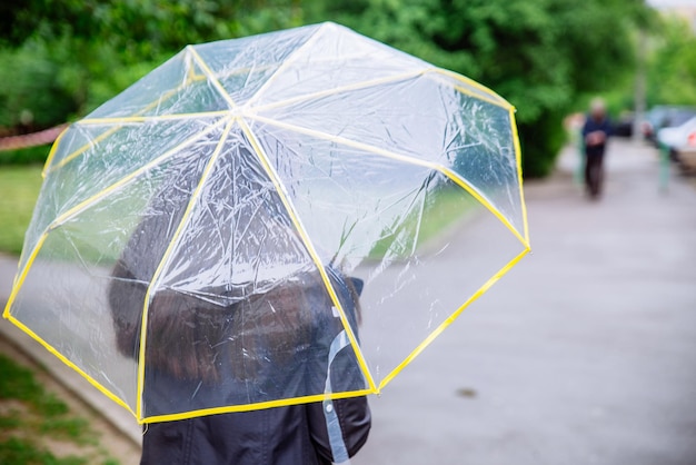 Vrouw met transparante paraplu regenachtig weer