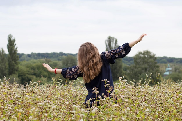 vrouw met uitgestrekte armen onder een pitchless veld in nationale kleding