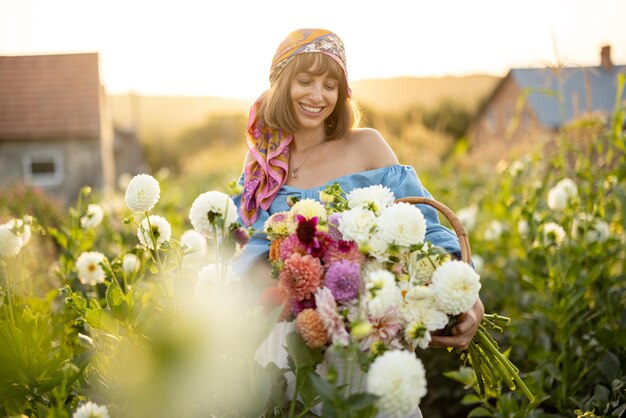 Vrouw met veel bloemen op dahlia boerderij buiten