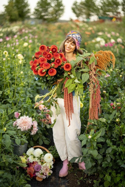 Vrouw met veel bloemen op dahlia boerderij buiten