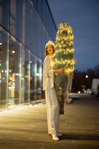 Vrouw met verlichte kerstboom bij het winkelcentrum