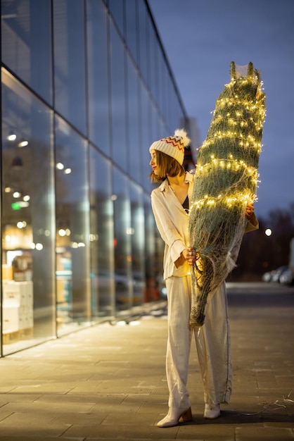 Vrouw met verlichte kerstboom in de buurt van het winkelcentrum