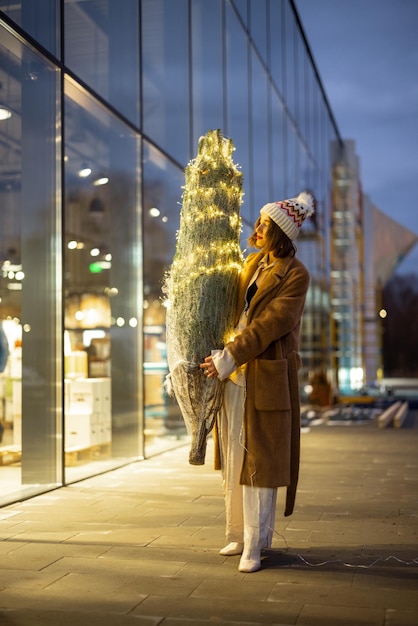 Vrouw met verlichte kerstboom in de buurt van het winkelcentrum