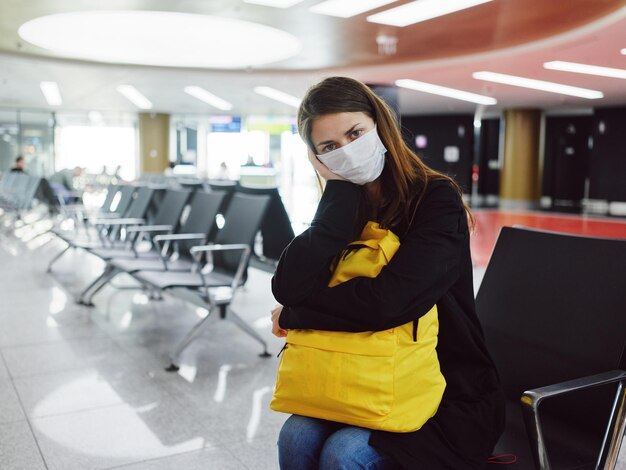 Vrouw met vermoeid gezichtsuitdrukking medisch masker wachtende luchthavenpassagier