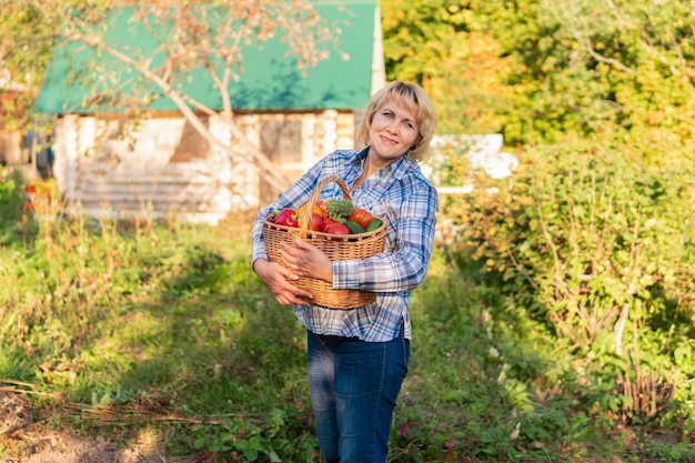 Vrouw met verse groenten in een mand in de tuin in de herfst