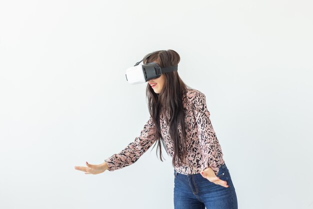 Vrouw met virtual reality-bril en een spel spelen tegen een witte muur met kopie ruimte