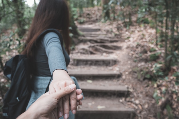 vrouw met vriendje hand terwijl trekking in tropisch bos