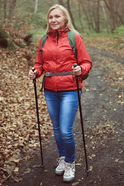 Foto vrouw met wandelstokken op bospad