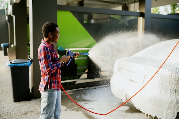 Vrouw met waterpistool met schuim, handwasstraat