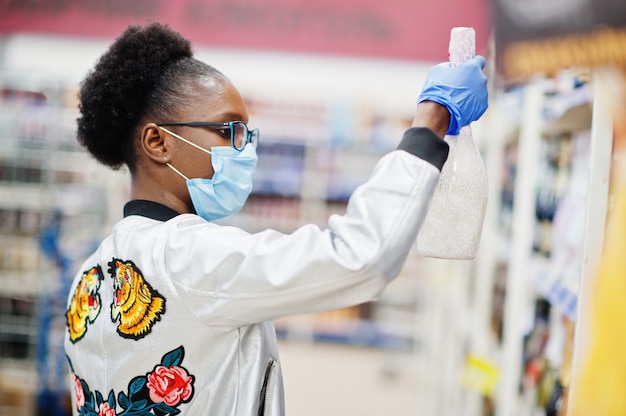 Vrouw met wegwerp medische masker en handschoenen winkelen in de supermarkt tijdens het uitbreken van een coronavirus pandemie.