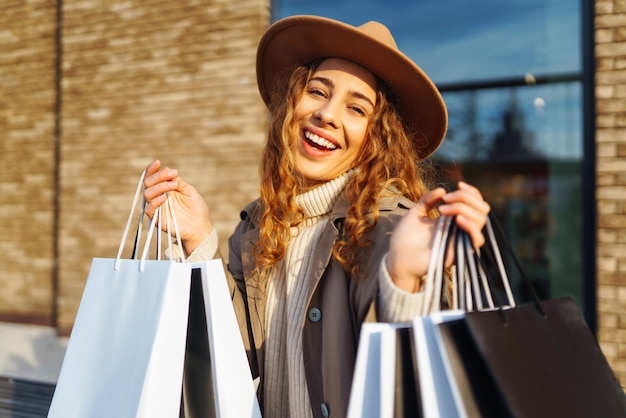 Vrouw met winkeltassen in de buurt van het winkelcentrum Consumentisme koopt winkelen levensstijl verkoop concept