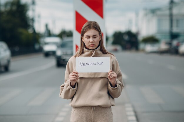 Vrouw met wit vel papier met het label woord Depressie in de hand.