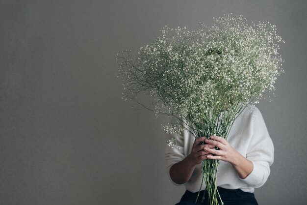 Vrouw met witte gipskruid bloeiende bloemen verstopt achter boeket