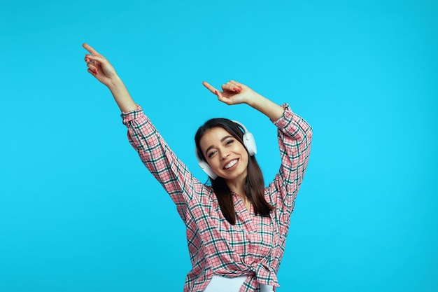 Vrouw met witte koptelefoon luistert naar muziek en danst met opgeheven handen