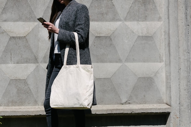 Vrouw met witte textiel totalisator eco tas in stedelijk gebied