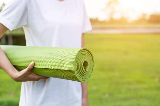 Vrouw met yogamat in het park