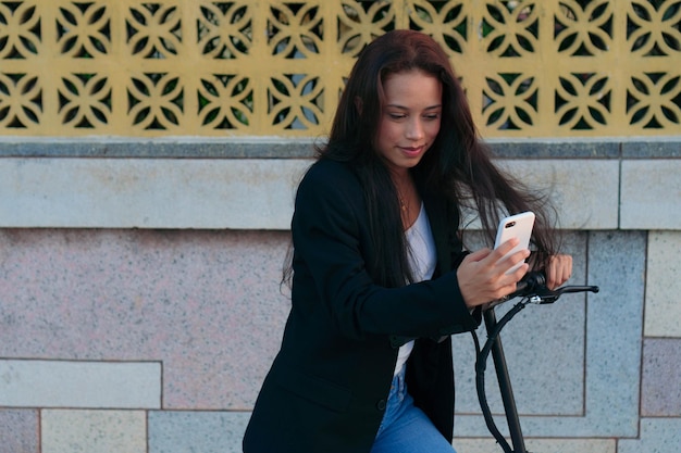 Vrouw met zijn mobiele telefoon en elektrische scooter die hij huurde in de stad Deze manier van vervoer maakt het heel gemakkelijk om je te verplaatsen.