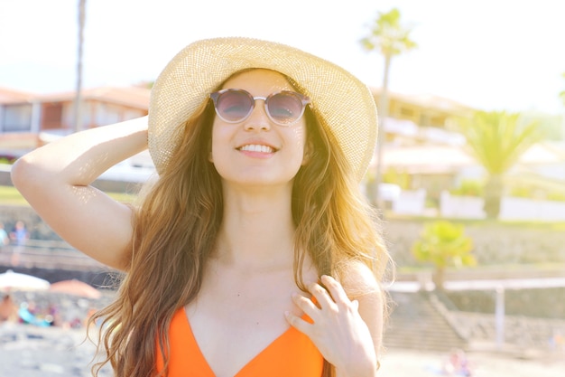Vrouw met zonnebril en hoed genieten van zon op het strand
