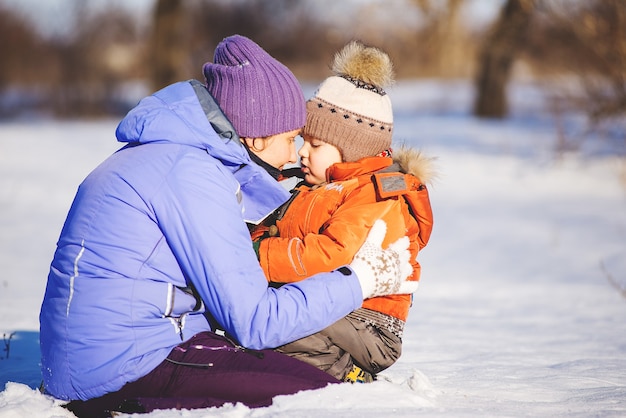 Vrouw met zoontje spelen in het park in de winter op sneeuw.