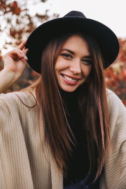 Vrouw met zwarte hoed buiten in de herfst